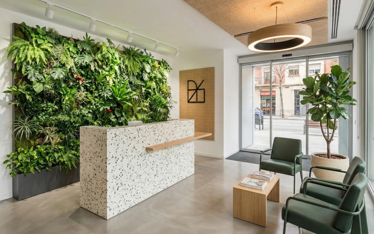 Recepción con muro vegetal y mostrador de terrazzo